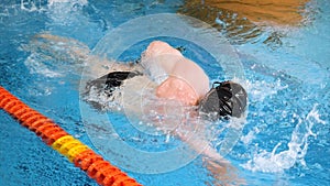 Close up for professional swimmer in slow mothion while diving in indoor pool. Athlete training, diving under the water