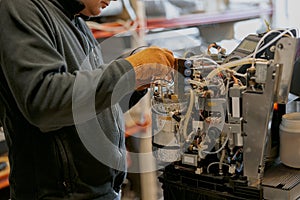 Professional worker fixing coffee machine in workshop