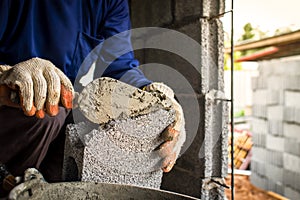 Close-up of a professional worker using a pan knife to build a brick wall with cement bricks and cement.