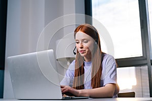 Close-up of professional young woman operator using headset and laptop during customer support at home office.