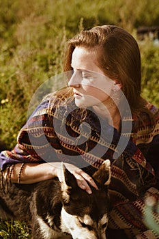 close-up. Profile of a beautiful girl with natural beauty sitting among the grass in a hug with a dog