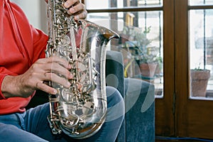 close up in profile with copy space of male hands playing a saxophone inside home