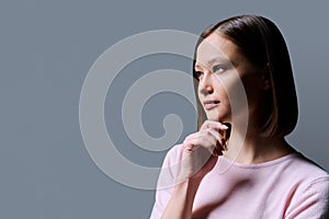 Close-up profile portrait of young beautiful woman on gray background