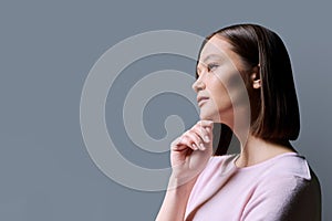 Close-up profile portrait of young beautiful woman on gray background