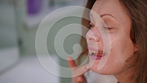 Close-up. Profile of a woman's face with morning makeup. A woman applies cream to her face with her finger while