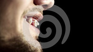 Close up profile of a young man with braces on teeth black background.