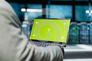 Close up of programmer in data center using green screen laptop