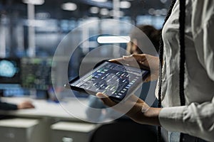 Close up of programmer in data center using tablet, managing AI datasets