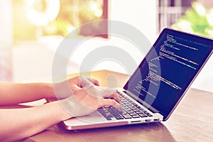 Close-up of programmer`s hands working on source codes over a laptop outdoors.
