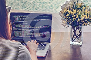 Close-up of programmer`s hands working on source codes over a laptop on a summer day.