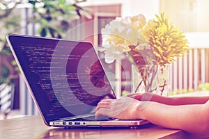 Close-up of programmer`s hands working on source codes over a laptop on a summer day.