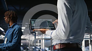 Close up of programmer swiping on tablet display in data center, checking code