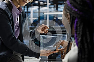 Close up of programmers coding on tablet in data center, updating AI scripts