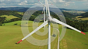 Close up a propeller of the windmill in the yellow field with mountains on the background.