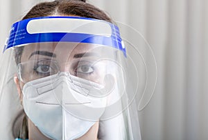 Close-up protrait of a nurse with face protection shield, glasses and N95 mask