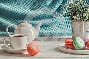 Close up. Provence breakfast. Colorful macarons on a round plate, a cup of berry tea, a lavender, a teapot.