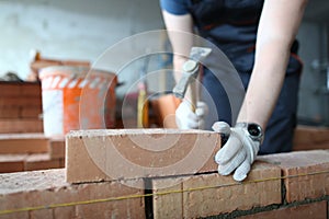 Skilled bricklayer putting red block