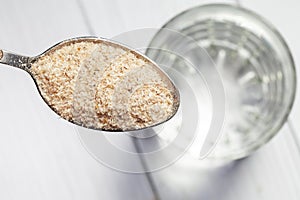 Close-up of psyllium or isabgol husk in a spoon on a glass of water, close-up, right above