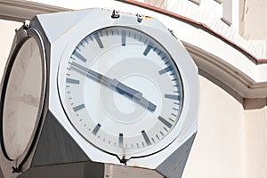 Close up on a public clock, with a vintage design from the 50s, indicating time, in the afternoon, with an anaolg round clock.