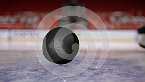 Close-up of puck falling on ice. Action. Puck slowly and epically falls to ice. Mesmerizing puck drop before impact