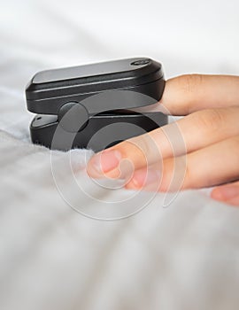 Close-up of pulse oximeter on woman`s finger with white background and copy space
