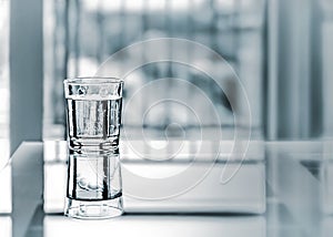 Close up purified fresh drink water with reflection on glass table in living room. Monochrome blurred background with copyspace.