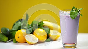 Close-up purple milkshake with berries and mint falling on citrus fruits at background in slow motion. Healthful