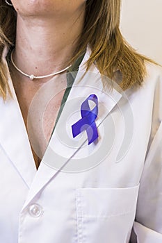Close-up of purple ribbon pinned on white lab coat of female doctor. Vertical shot