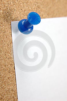 Close up of pushpin with blank note on corkboard