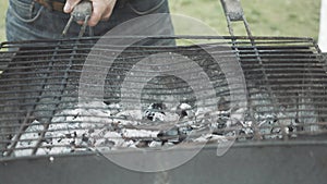 Close-up of putting barbecue grid on bbq. Unrecognizable Caucasian man cooking delicious fried food outdoors. Cookout