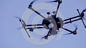 Close-up of quadcopter flying in sky. Clip. Large quadcopter with powerful motors flying on background blue sky