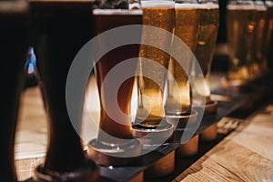 Close up of a rack of different kinds of beers, dark to light, on a table.