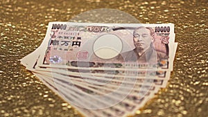 Close-up rack focus video on 100,000 yen in cash on a golden paper.