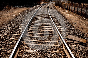 Close up of railway tracks passing or running straight through a forest type area with having surroundings dried out.