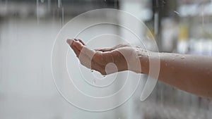 Close up the rain drop into woman's hand. Girl play with the rain in front of the house.