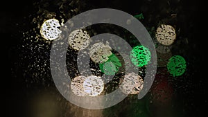 Close up. Raindrops on car windshield. Blurred background of traffic light.