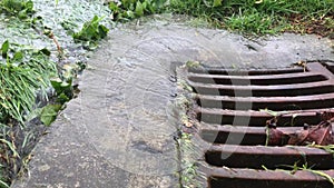 Close up of rainwater pouring into drain through metal grill