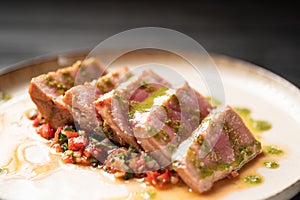 Close-up of rare tuna steak slices with roasted vegetable salad on a plate.