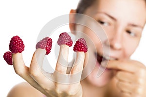 Close up of raspberries on fingers.