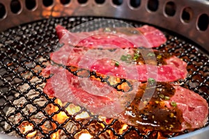 Close up raw beef slice on the grill ,over charcoal on stove,Japanese style Yakiniku