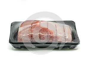 Close up raw cut of pork loin, tied up and rolled with butcher`s string in black plastic container, wrapped with plastic film