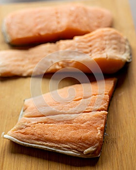 Close-up of raw, fresh salmon fillets arranged neatly on a wooden cutting board