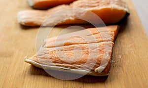 Close-up of raw, fresh salmon fillets arranged neatly on a wooden cutting board