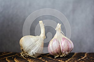 Close up of raw garlic on wooden cutting board on gray background, horisontal.