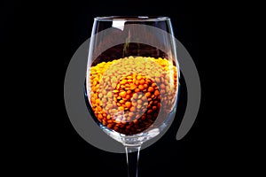 Close up of Raw Masur dal or masoor lentils or pink lentils in a black colored clay bowl on black in wineglass glass jar bucket
