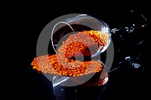 Close up of Raw Masur dal or masoor lentils or pink lentils in a black colored clay bowl on black in wineglass glass jar bucket