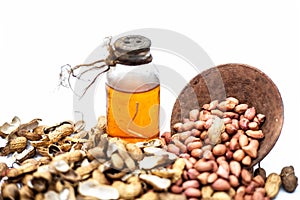 Close up of raw organic peanuts or ground nuts isolated on white along with its herbal organic extracted oil in a transparent bott