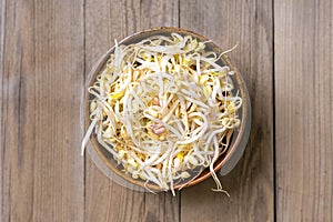 Close up of raw pile of sprouted seeds of green gram in bowl on wooden background
