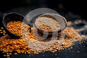 Close up of raw pink lentils in a clay bowl on wooden surface with its powder.