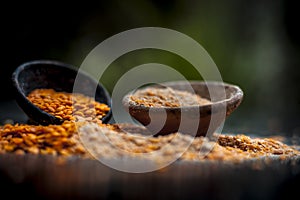 Close up of raw pink lentils in a clay bowl on wooden surface with its powder.